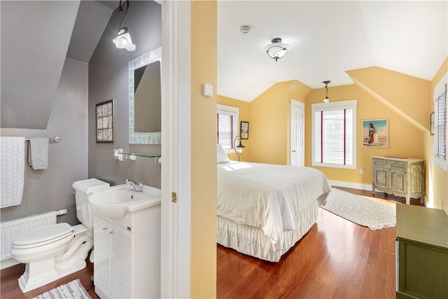 bedroom featuring hardwood / wood-style flooring, lofted ceiling, sink, and radiator