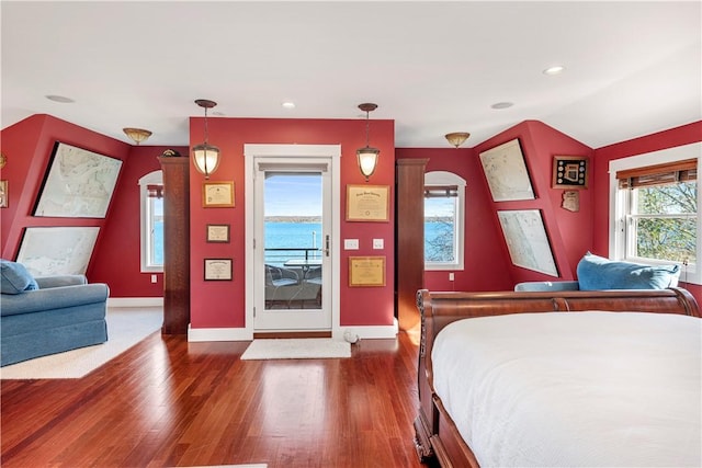 bedroom with access to exterior, dark hardwood / wood-style floors, vaulted ceiling, and a water view