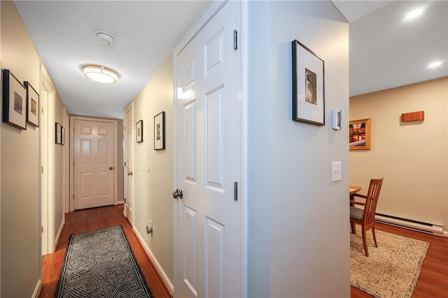 hall featuring a textured ceiling, baseboard heating, and dark wood-type flooring