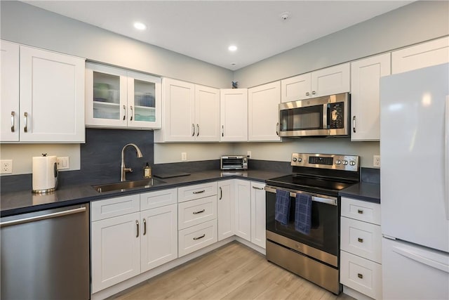 kitchen featuring white cabinets, light wood-type flooring, stainless steel appliances, and sink