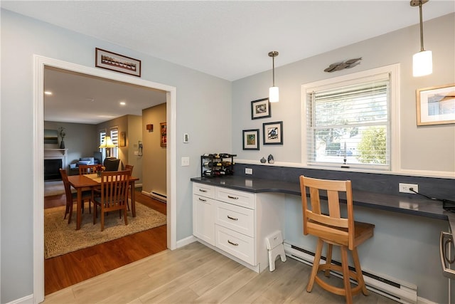 kitchen with pendant lighting, white cabinetry, light hardwood / wood-style flooring, and a baseboard radiator