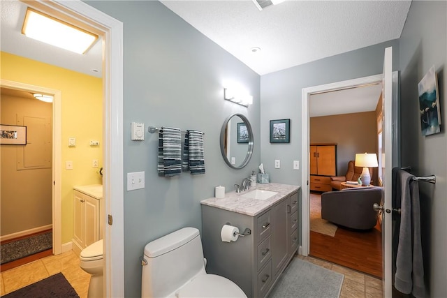 bathroom with tile patterned floors, vanity, toilet, and a textured ceiling