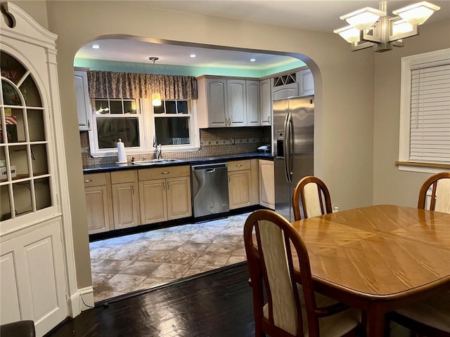 kitchen with sink, decorative backsplash, appliances with stainless steel finishes, decorative light fixtures, and wood-type flooring