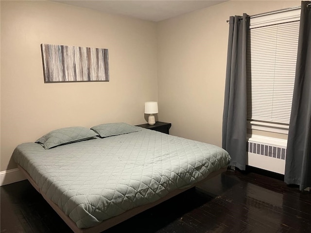 bedroom with dark hardwood / wood-style flooring and radiator