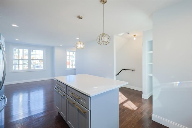 kitchen featuring pendant lighting, gray cabinetry, dark hardwood / wood-style floors, a notable chandelier, and a kitchen island