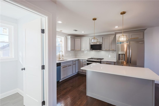 kitchen with dark hardwood / wood-style flooring, hanging light fixtures, gray cabinetry, and stainless steel appliances