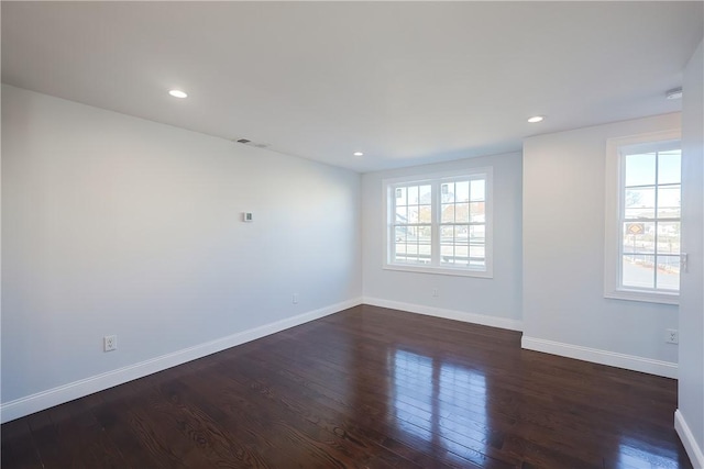 spare room featuring a wealth of natural light and dark hardwood / wood-style flooring