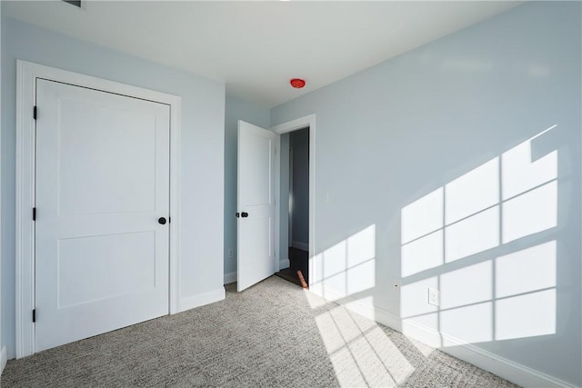 unfurnished bedroom featuring light colored carpet and a closet