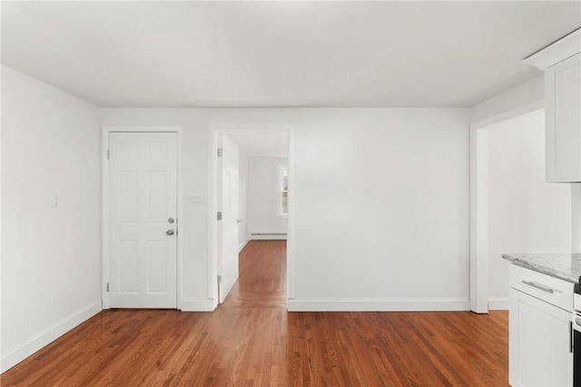 spare room with hardwood / wood-style floors and a baseboard heating unit