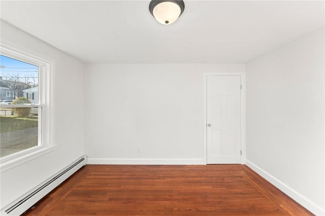 empty room featuring dark hardwood / wood-style flooring and a baseboard heating unit