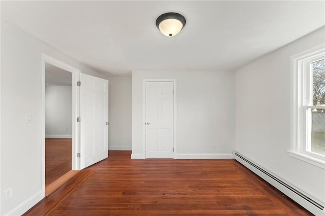 unfurnished room with dark hardwood / wood-style flooring and a baseboard radiator