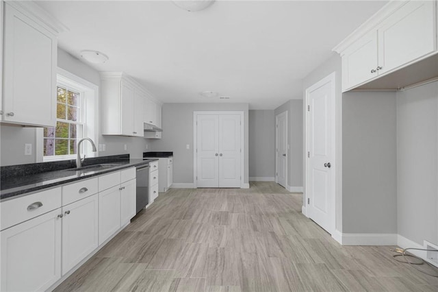 kitchen featuring white cabinets, light hardwood / wood-style flooring, stainless steel dishwasher, and dark stone countertops