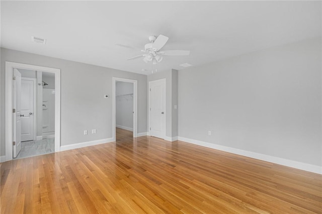 unfurnished bedroom featuring connected bathroom, ceiling fan, a spacious closet, light hardwood / wood-style floors, and a closet