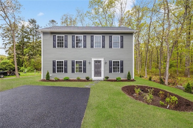 colonial-style house featuring a front lawn