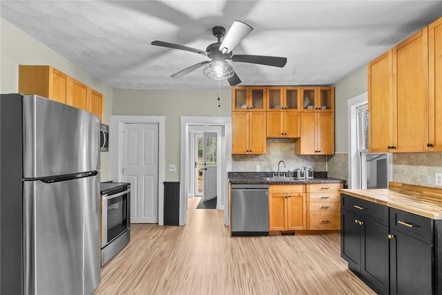 kitchen featuring ceiling fan, sink, tasteful backsplash, light hardwood / wood-style flooring, and appliances with stainless steel finishes