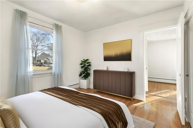 bedroom with baseboard heating and light hardwood / wood-style floors