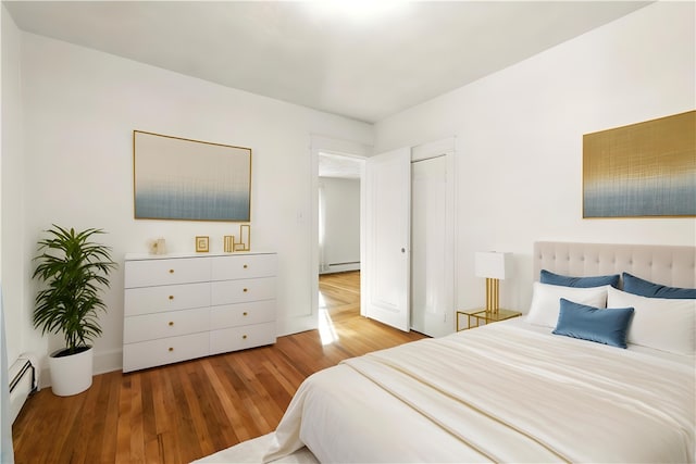 bedroom with a baseboard radiator and hardwood / wood-style flooring