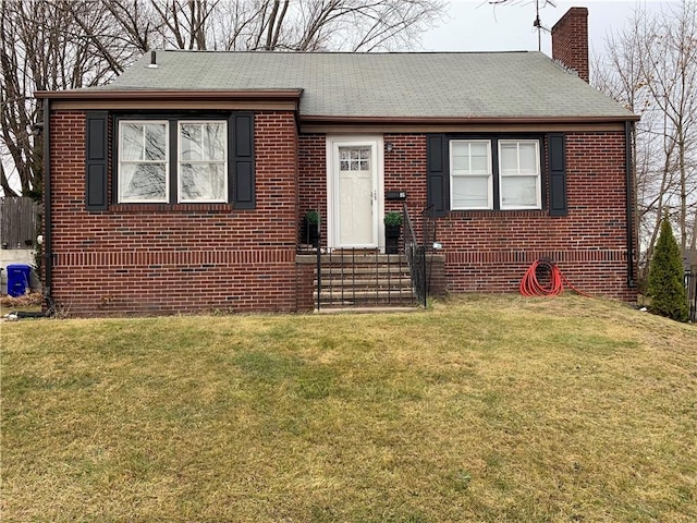 view of front facade with entry steps, brick siding, a chimney, and a front lawn