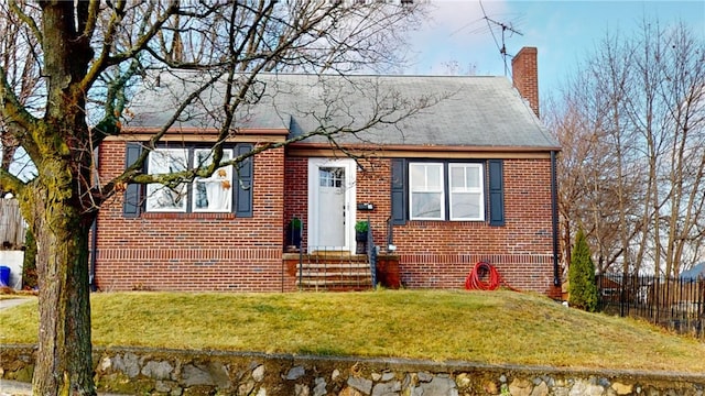 view of front of house featuring entry steps, a chimney, a front lawn, and brick siding