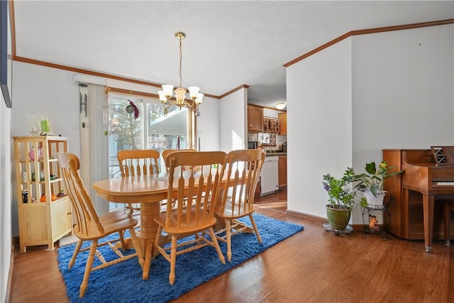 dining room with a textured ceiling, a notable chandelier, light wood-type flooring, and crown molding