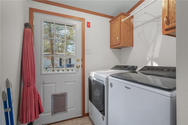 clothes washing area featuring cabinets, ornamental molding, and washing machine and clothes dryer