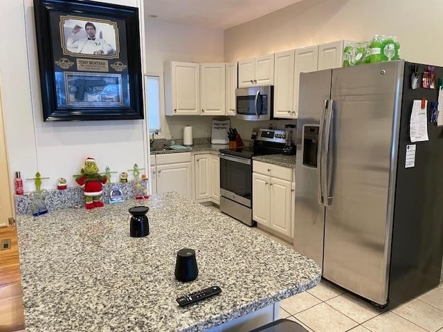 kitchen featuring white cabinetry, light hardwood / wood-style flooring, stainless steel appliances, and light stone counters