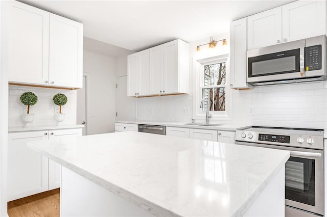 kitchen featuring light wood-type flooring, backsplash, stainless steel appliances, sink, and white cabinetry