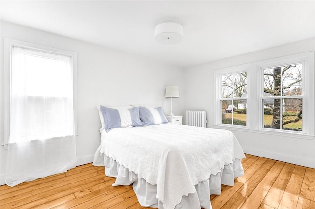 bedroom featuring multiple windows, light hardwood / wood-style flooring, and radiator