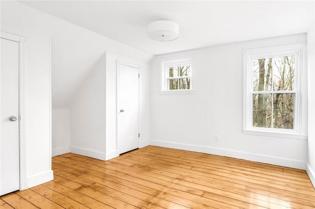 additional living space with light wood-type flooring and vaulted ceiling