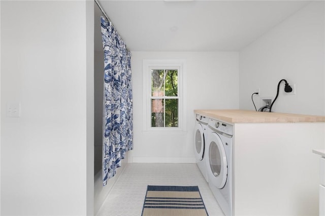 clothes washing area featuring light tile patterned flooring and washer and dryer