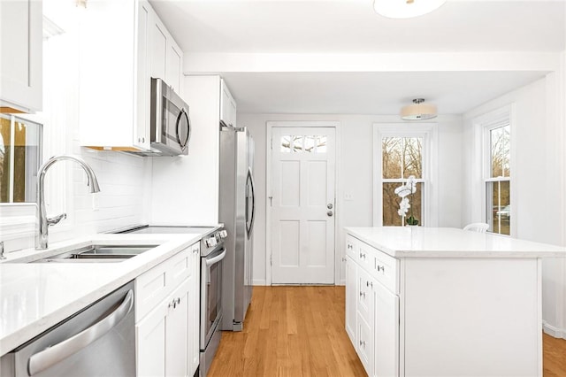 kitchen with tasteful backsplash, white cabinetry, light hardwood / wood-style flooring, and stainless steel appliances