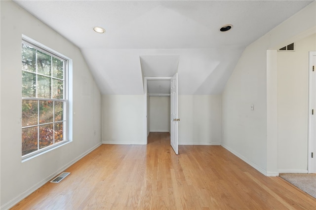 bonus room with light hardwood / wood-style flooring, vaulted ceiling, and plenty of natural light