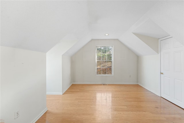 additional living space featuring light wood-type flooring and vaulted ceiling