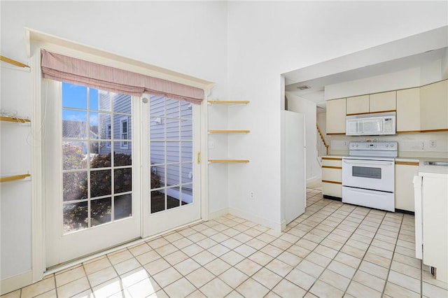 kitchen featuring cream cabinets, white appliances, and light tile patterned floors