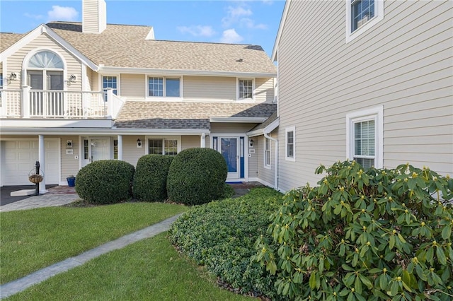 view of front of home featuring a garage, a balcony, and a front yard