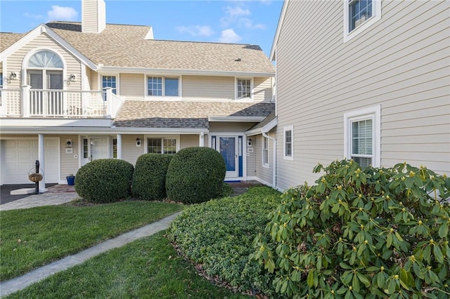 view of front of home featuring a balcony, a garage, and a front lawn