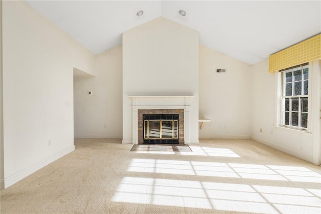 unfurnished living room with light carpet, vaulted ceiling, and a tiled fireplace