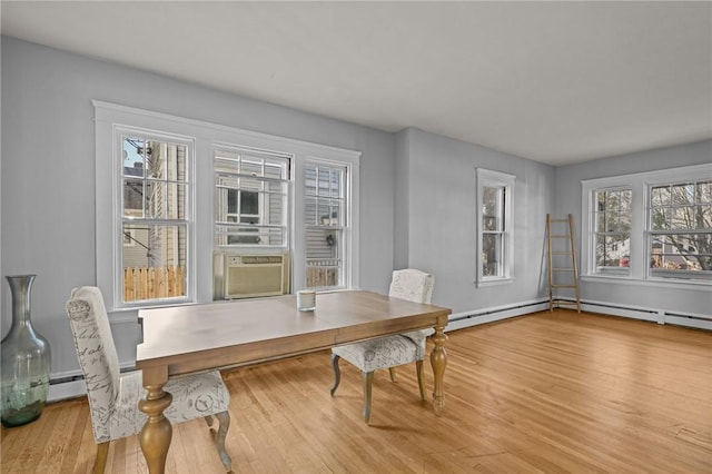 dining area featuring plenty of natural light, cooling unit, wood-type flooring, and a baseboard heating unit