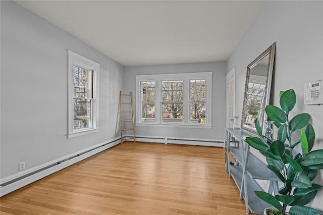 empty room with hardwood / wood-style floors and a baseboard heating unit