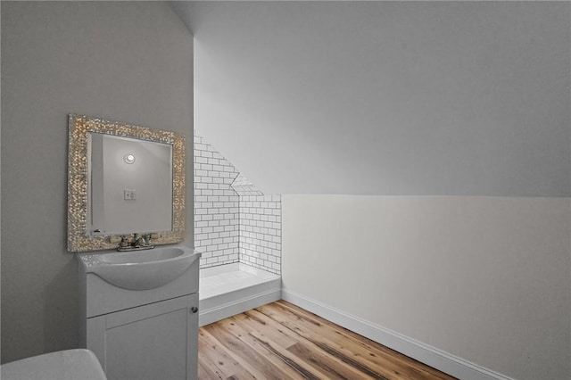 bathroom featuring a shower, vanity, wood-type flooring, and vaulted ceiling