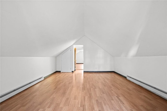 additional living space featuring a baseboard radiator, lofted ceiling, and light wood-type flooring