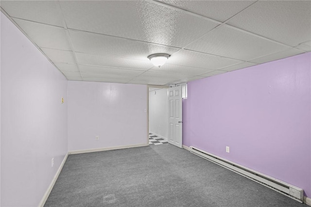 basement with a paneled ceiling, carpet floors, and a baseboard heating unit