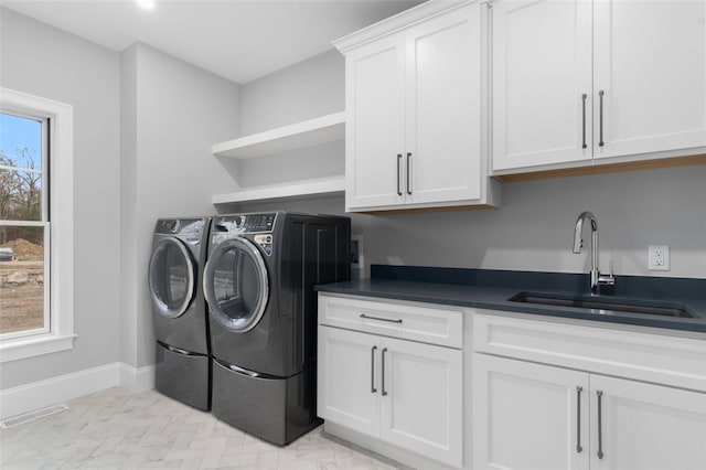 washroom with cabinets, washing machine and dryer, and sink