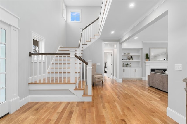 stairs featuring built in shelves, crown molding, hardwood / wood-style floors, and plenty of natural light