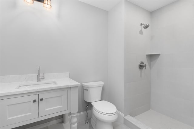 bathroom featuring tiled shower, vanity, toilet, and tile patterned flooring