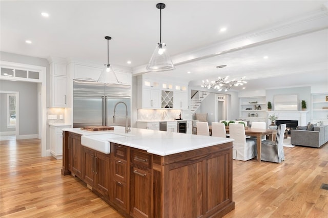 kitchen featuring a center island with sink, white cabinets, sink, light hardwood / wood-style flooring, and stainless steel appliances