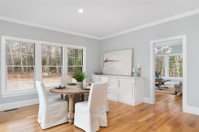 dining space featuring a healthy amount of sunlight, light wood-type flooring, and ornamental molding