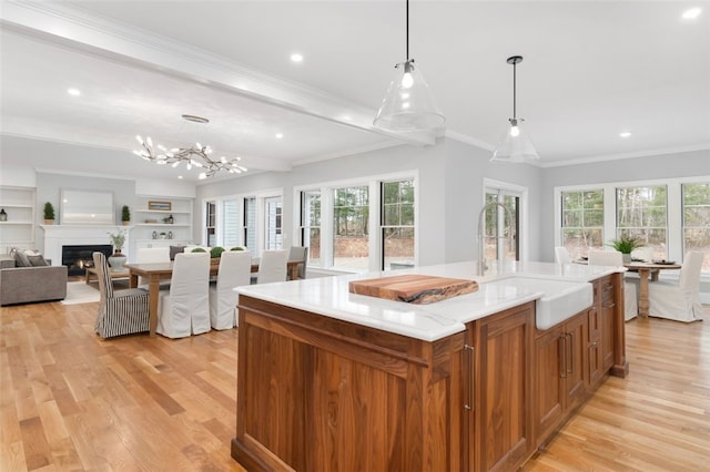 kitchen featuring hanging light fixtures, a center island, light wood-type flooring, and sink