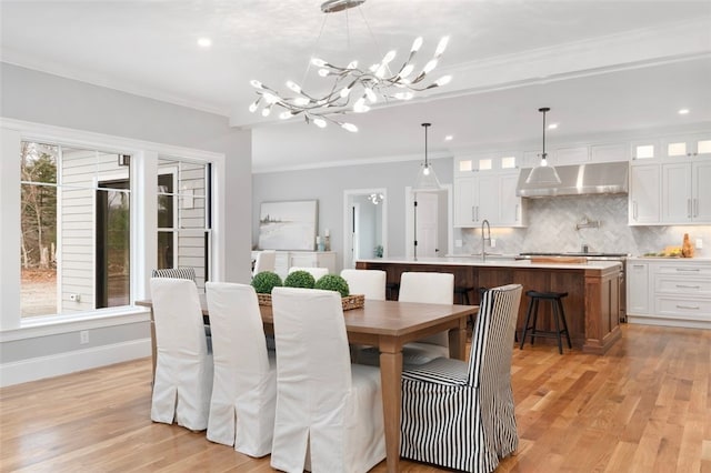 dining area featuring a healthy amount of sunlight, light wood-type flooring, ornamental molding, and a chandelier