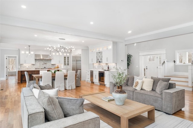 living room featuring beverage cooler, ornamental molding, and light wood-type flooring